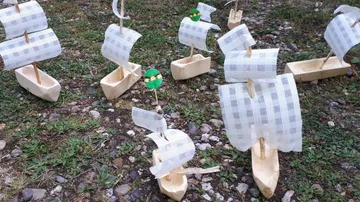 Holzspielzeugschiffe auf grasigem und steinigem Boden.