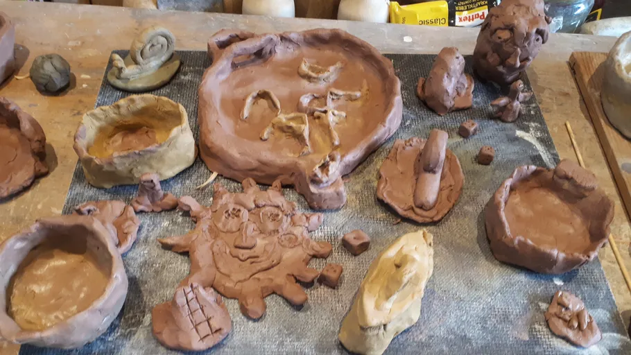 Clay sculptures on workbench, various shapes.