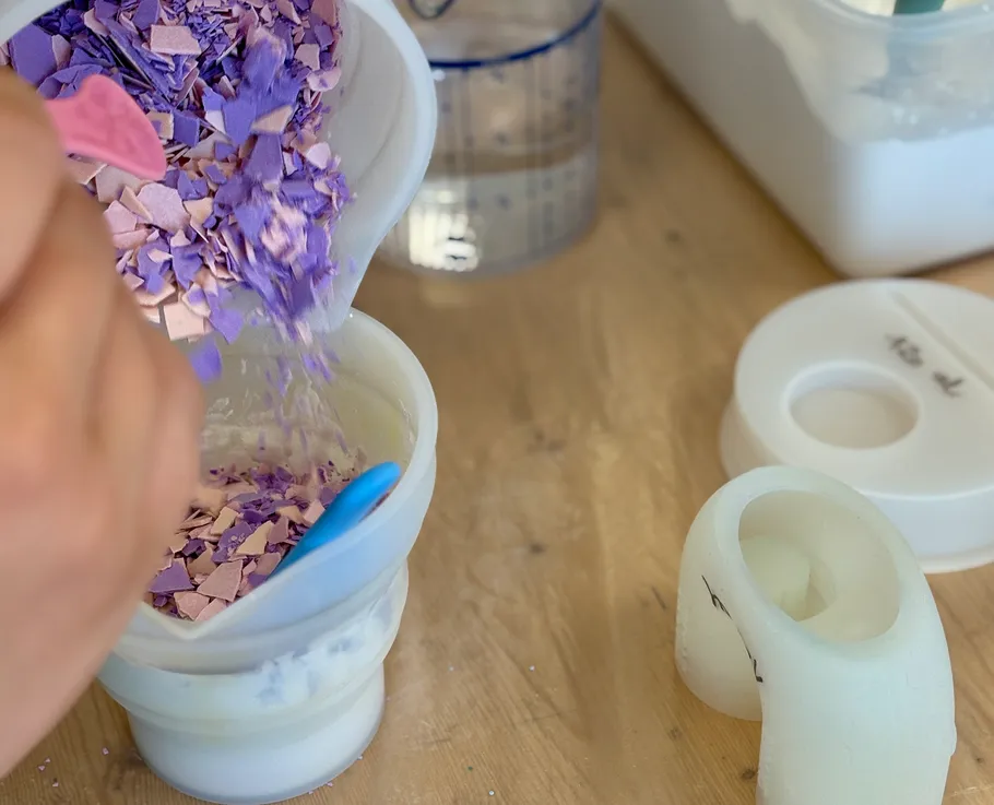 Hand stirring colored flakes in a container.