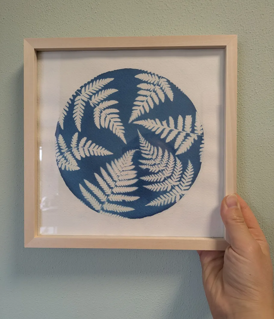 Framed fern art held against a wall.