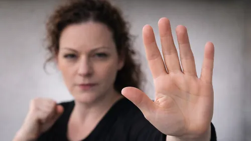 Frau hebt Hand, konzentrierter Blick, Innenraum.