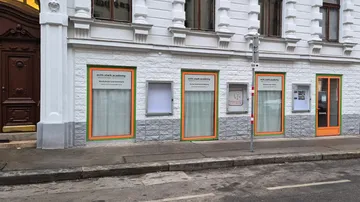 Building facade with academy windows and signs.