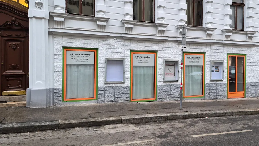 Building facade with academy windows and signs.