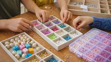 Hände ordnen bunte Perlen auf Tisch.