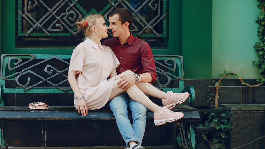 Couple sitting closely on outdoor bench.