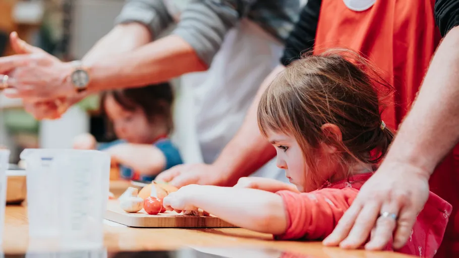 Kinder schneiden Gemüse mit Aufsicht.