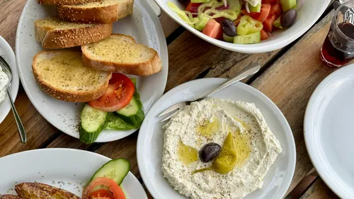 Brot, Salat und Dip auf Holztisch.