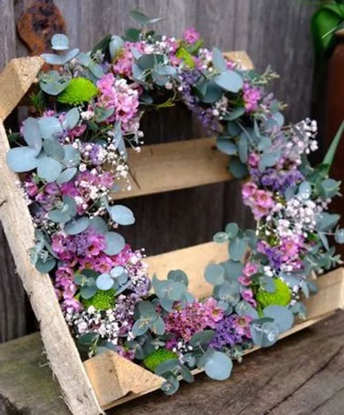 Floral wreath on wooden structure outdoors.