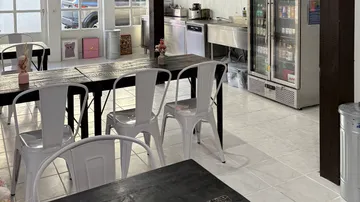 Leeres Café mit Tischen, Stühlen und Kühlschrank.