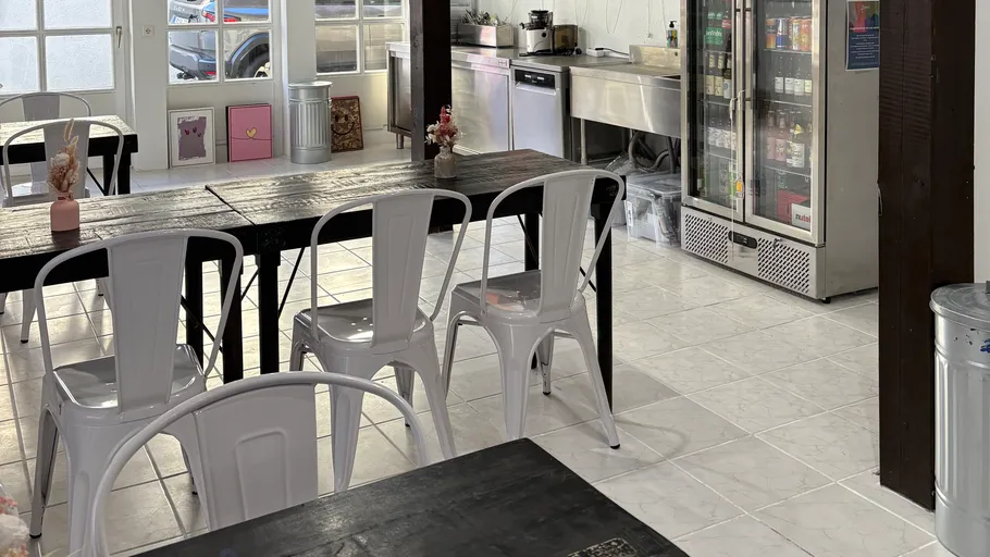 Leeres Café mit Tischen, Stühlen und Kühlschrank.