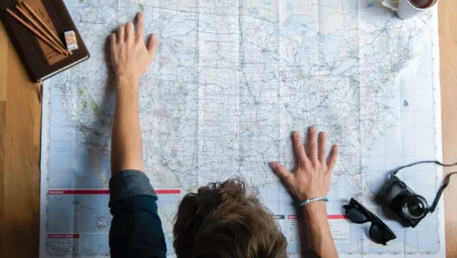 Person examining map on wooden table.