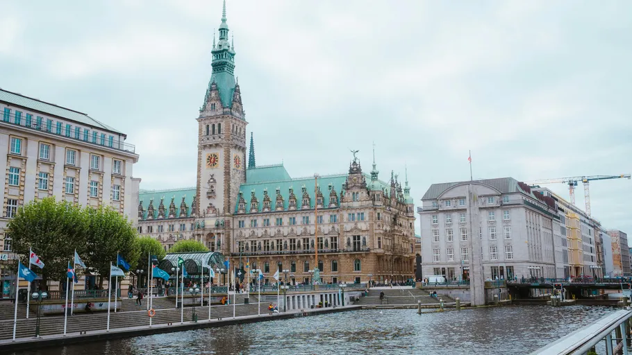 Historic building with tower beside river and bridge.
