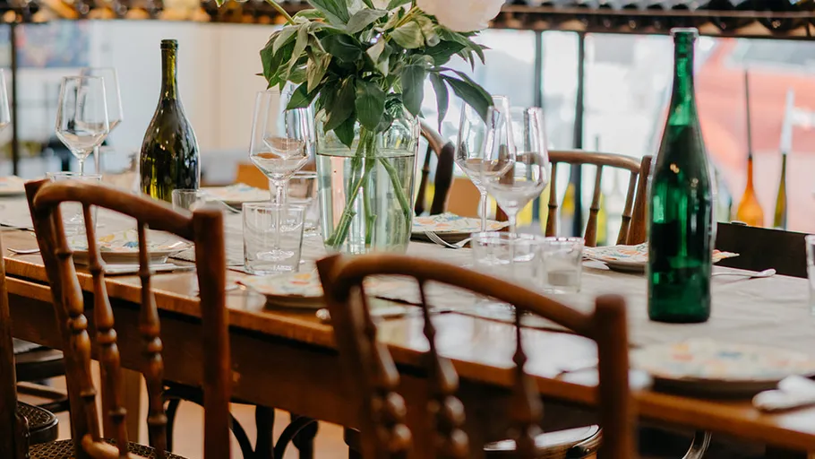 Table with wine bottles and glasses indoors.
