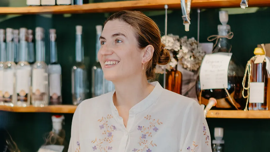 Woman smiling in front of shelves with bottles.