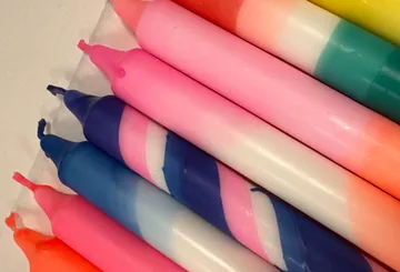 Colorful striped candles on white surface.