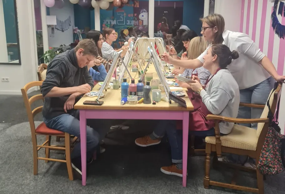 Gruppe malt an Tischen im Kunststudio.