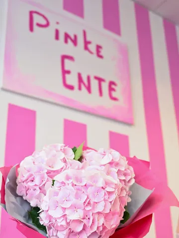 Pink flowers in front of striped wall.