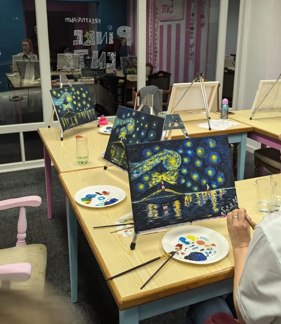 Paintings on easels in art class setting.