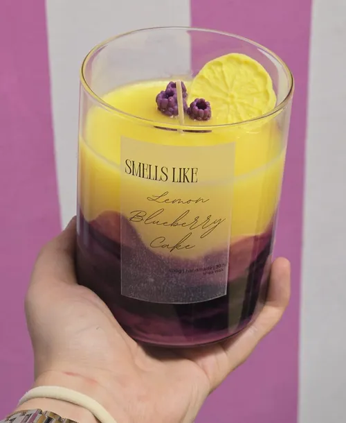 Hand holding scented candle with label.