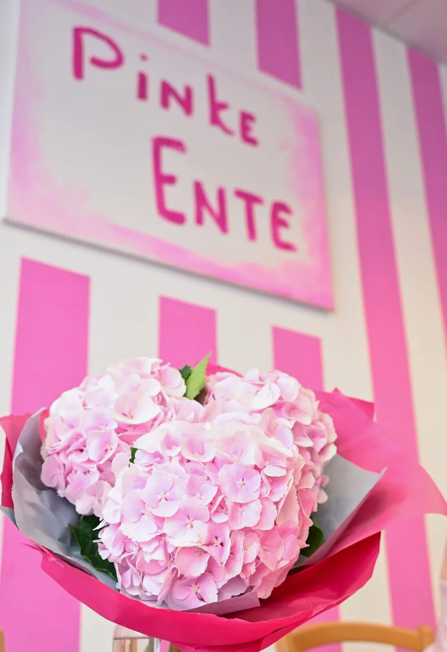 Pink flowers bouquet inside pink-striped room.