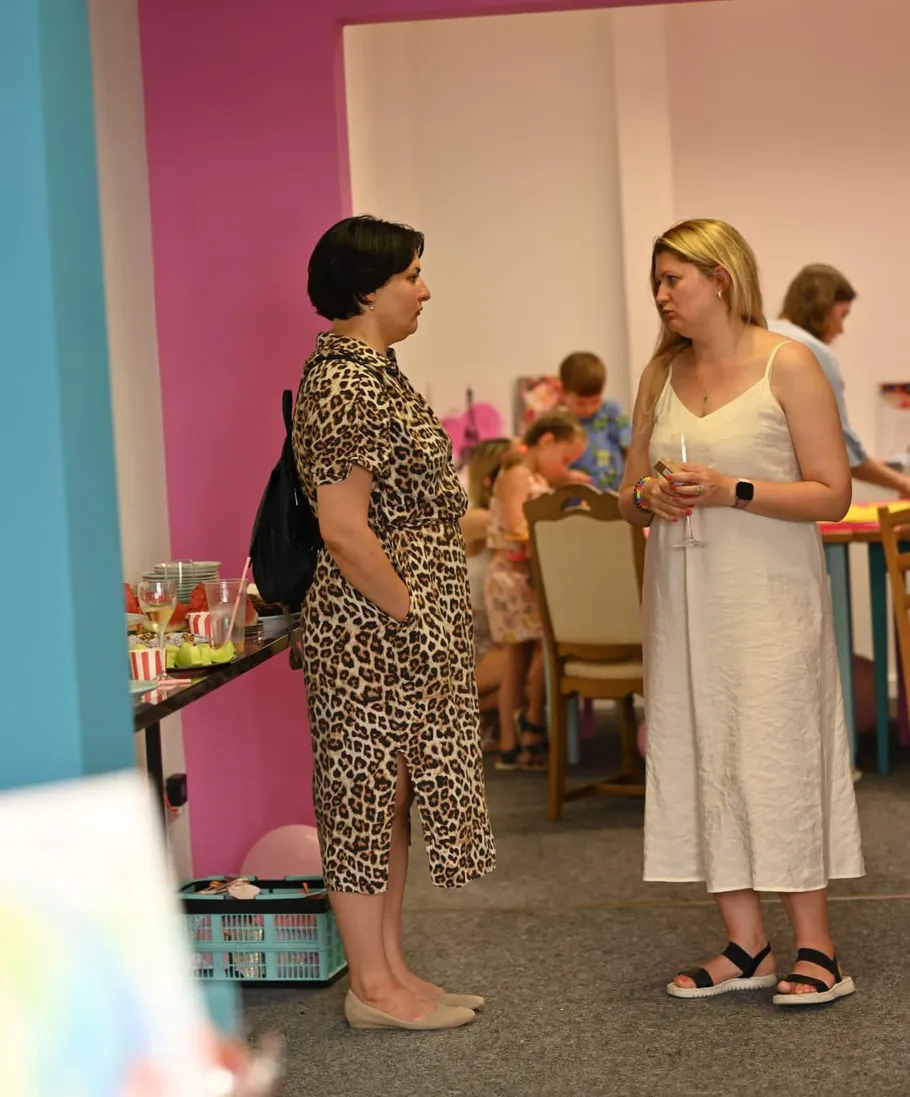 Zwei Frauen sprechen in einem bunten Raum.