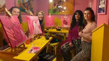 Four women painting in a colorful studio.