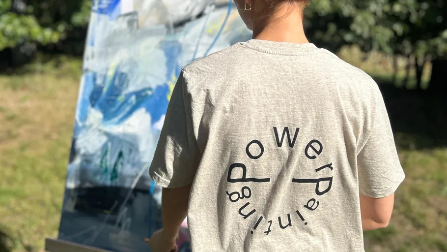 Person painting outdoors with abstract art canvas.