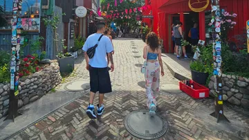 Zwei Personen gehen in buntem Straßenmarkt.
