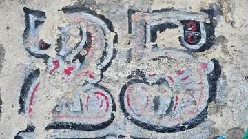 Graffiti-Zahl 25 auf einer verwitterten Wand.