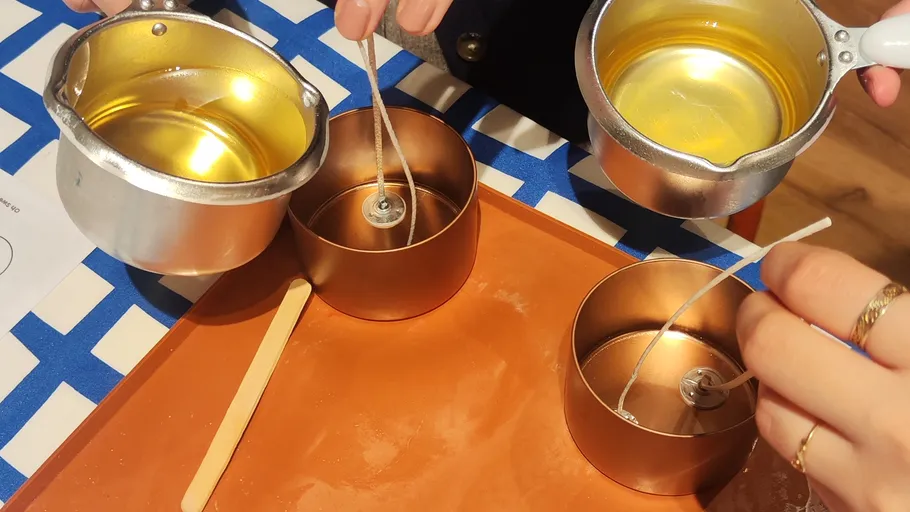 People pouring wax into candle containers.