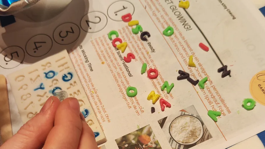 Hand ordnet Buchstaben auf farbigem Papierhintergrund an.