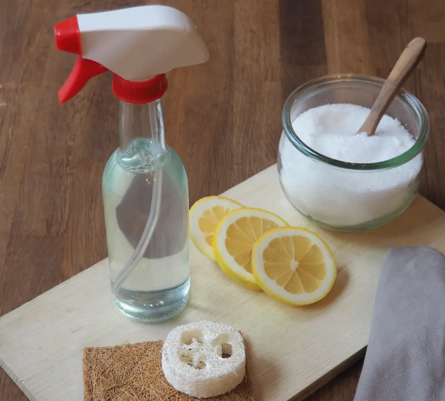 Sprühflasche mit Zitronen und Salz auf Tisch.