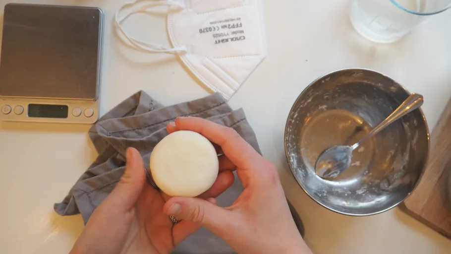 Hände halten Teig nahe Schüssel und Maske.