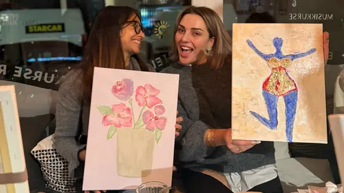 Zwei Frauen halten ihre Gemälde in einem Café.