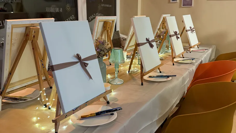 Easels with canvases on a decorated table.