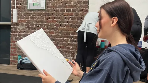 Person painting on canvas in art class.