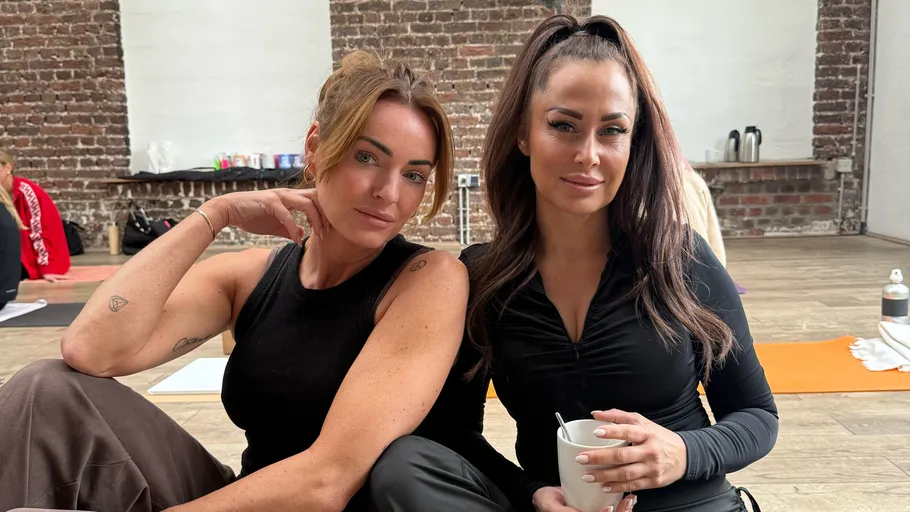 Two women sitting, one holding a mug.