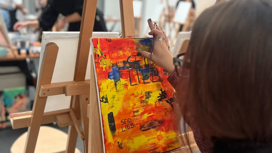 Woman painting colorful canvas at art class.