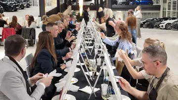 People painting at canvases in a car showroom.