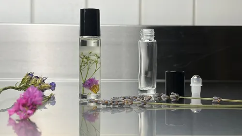 Glasflaschen mit Blumen auf reflektierender Fläche.