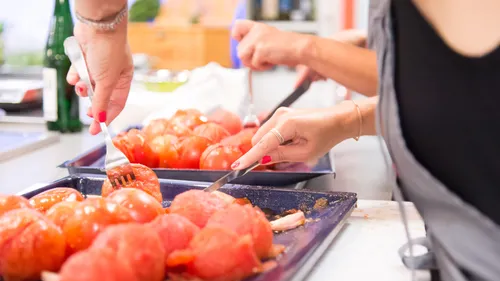 Personen bereiten Tomaten in der Küche vor.