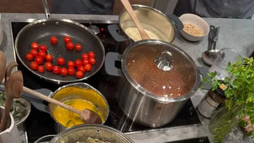 Multiple pots and pans cooking ingredients on stove.