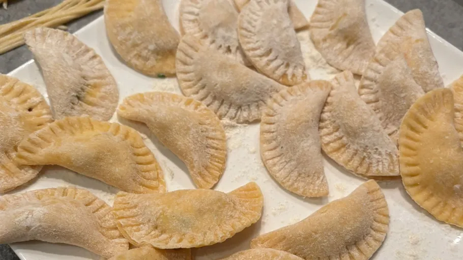 Uncooked dumplings arranged on white plate.
