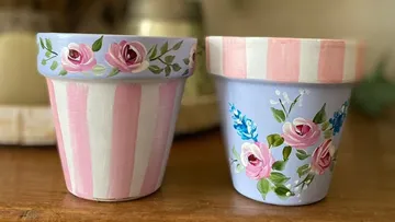 Zwei bemalte Blumentöpfe mit Rosendesigns.