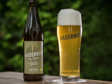 Flasche und Glas Bier stehen auf einem Tisch im Freien.