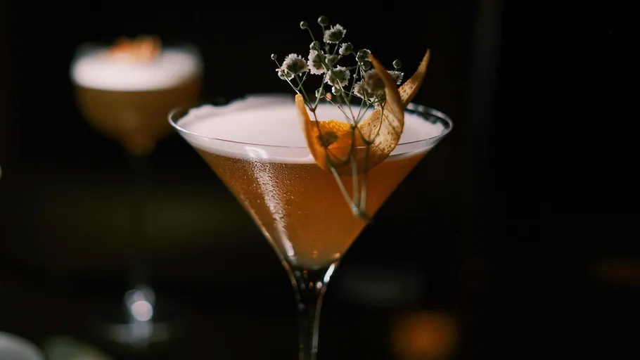 Cocktail glass with garnish in dim light.