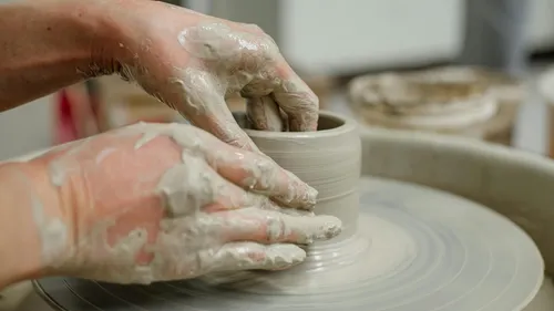 Hands shaping clay on a pottery wheel.