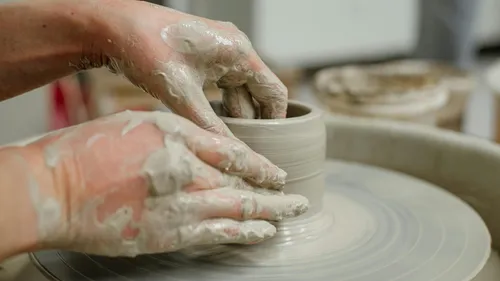 Hands shaping clay on a pottery wheel.