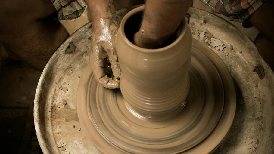 Hands shaping clay on a potter's wheel.