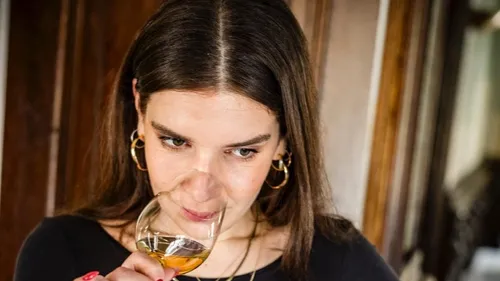 Woman smells wine in a glass, indoors.